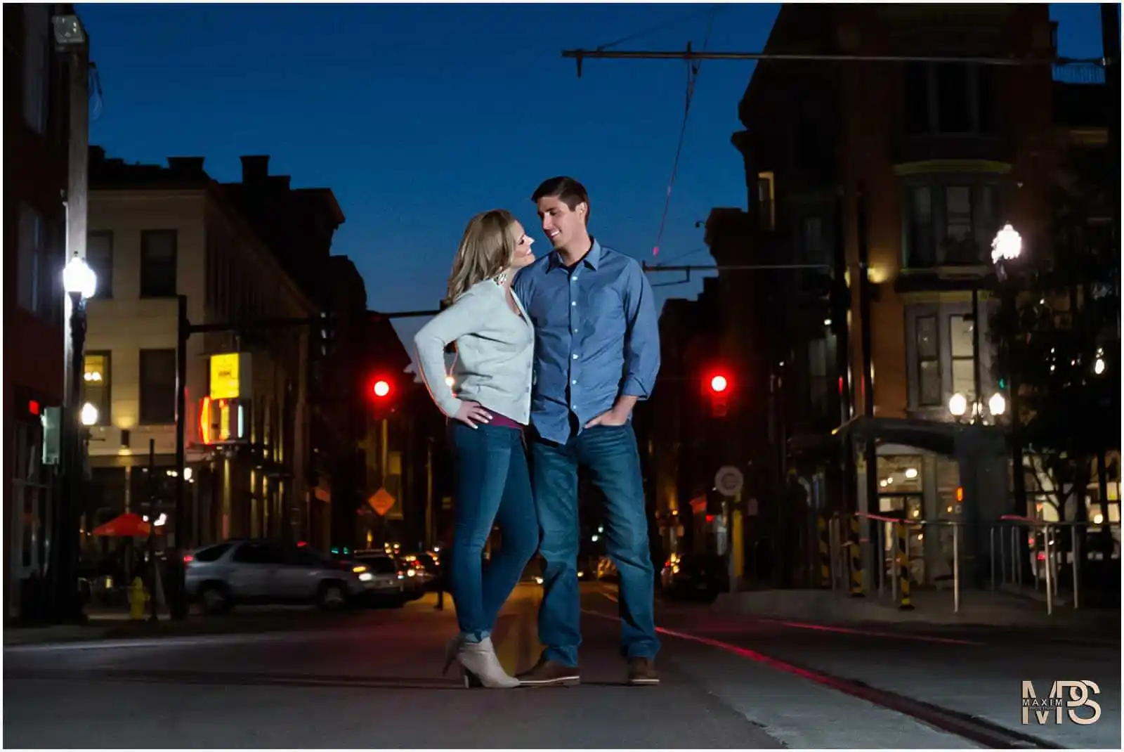 Romantic couple embracing on vibrant city street at night.