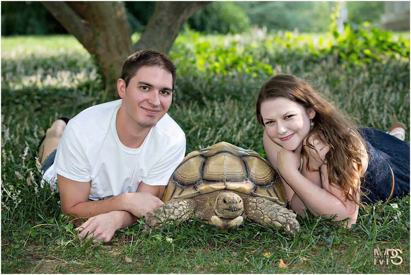 Happy couple posing with a pet tortoise outdoors.