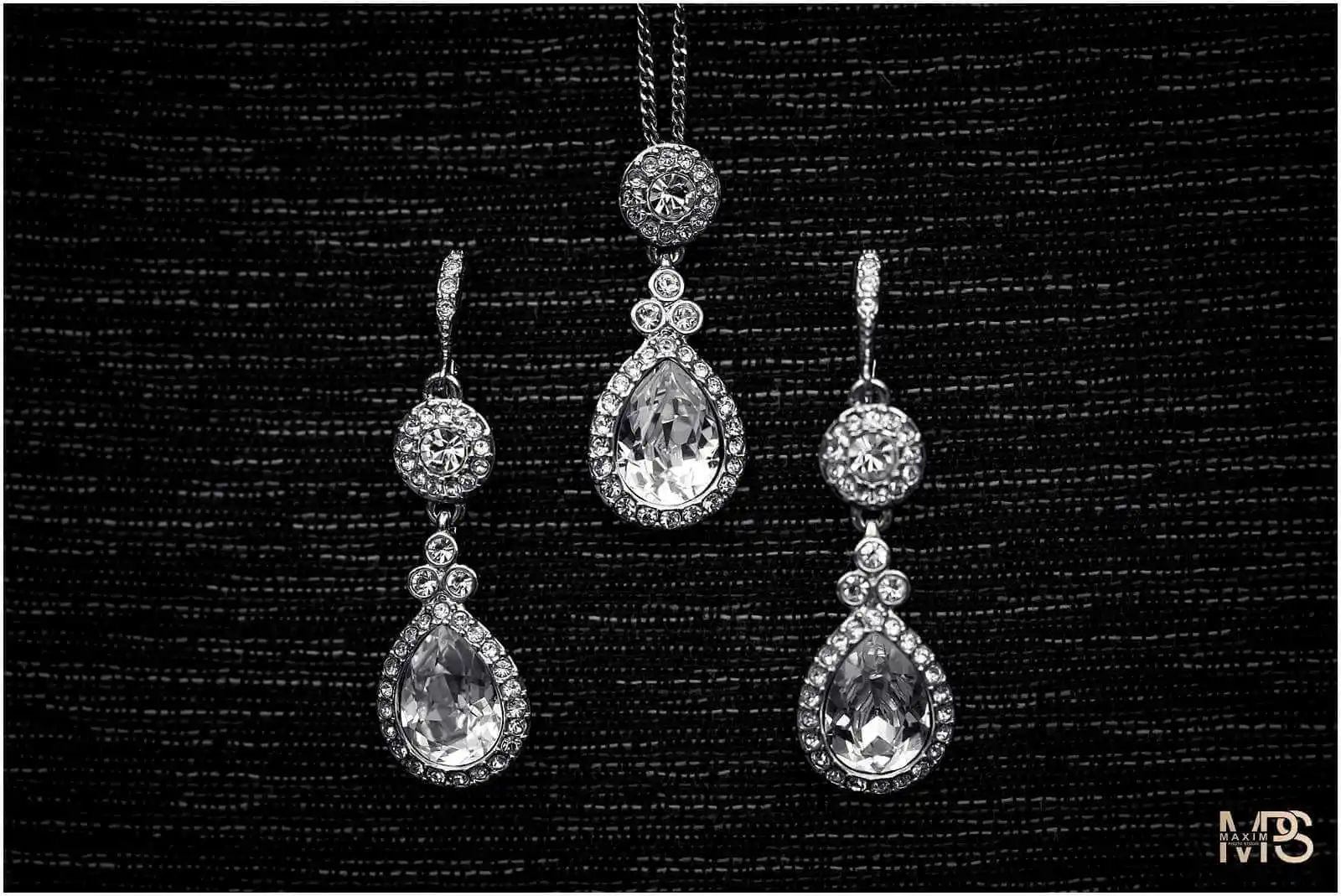 Elegant diamond necklace and earrings set on black background.