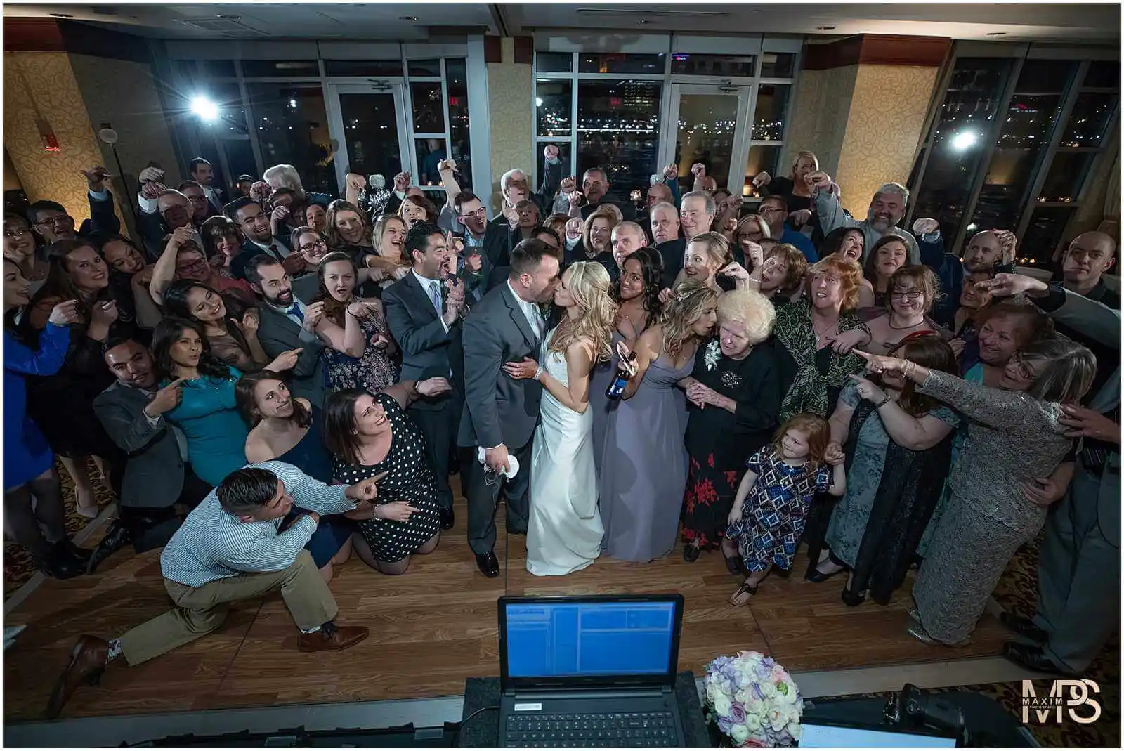 Energetic wedding reception with happy guests celebrating around the bride and groom.