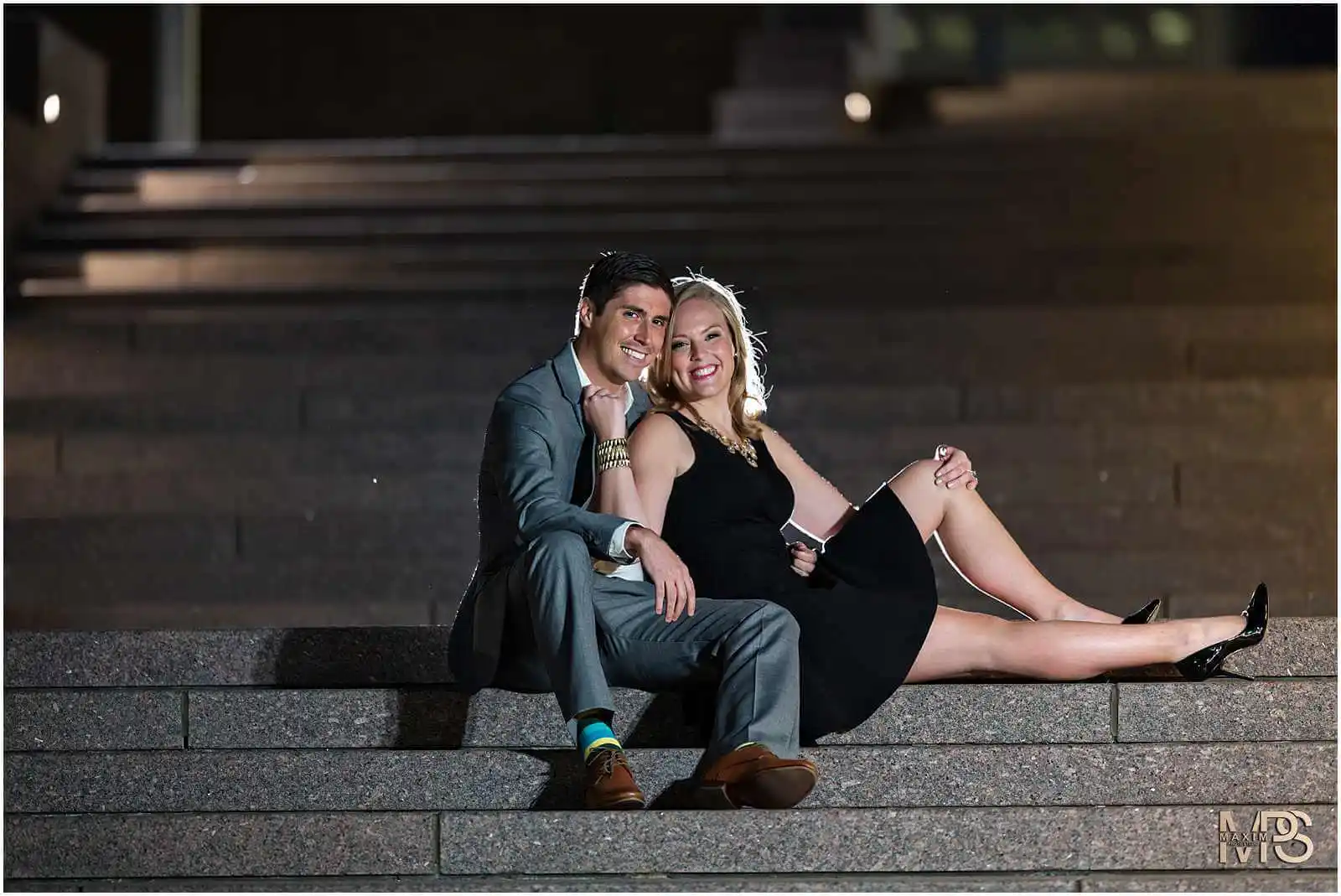 Romantic couple posing on stairs at night.