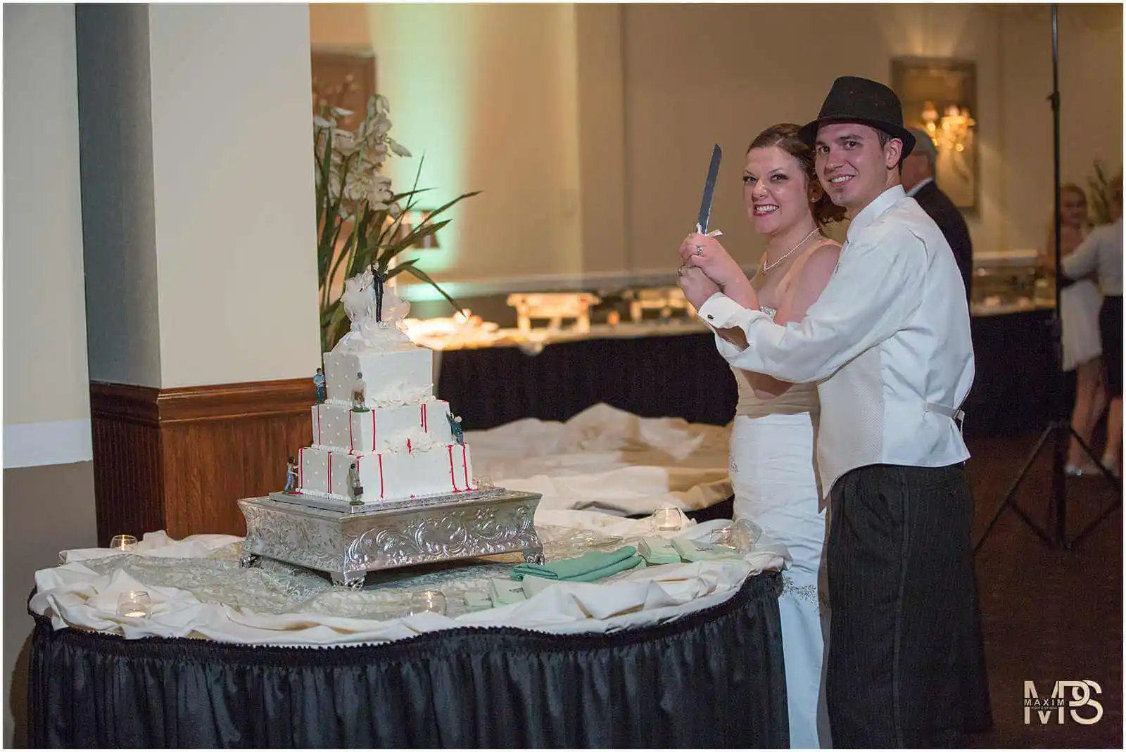 Bride and groom cutting multi-tiered wedding cake.