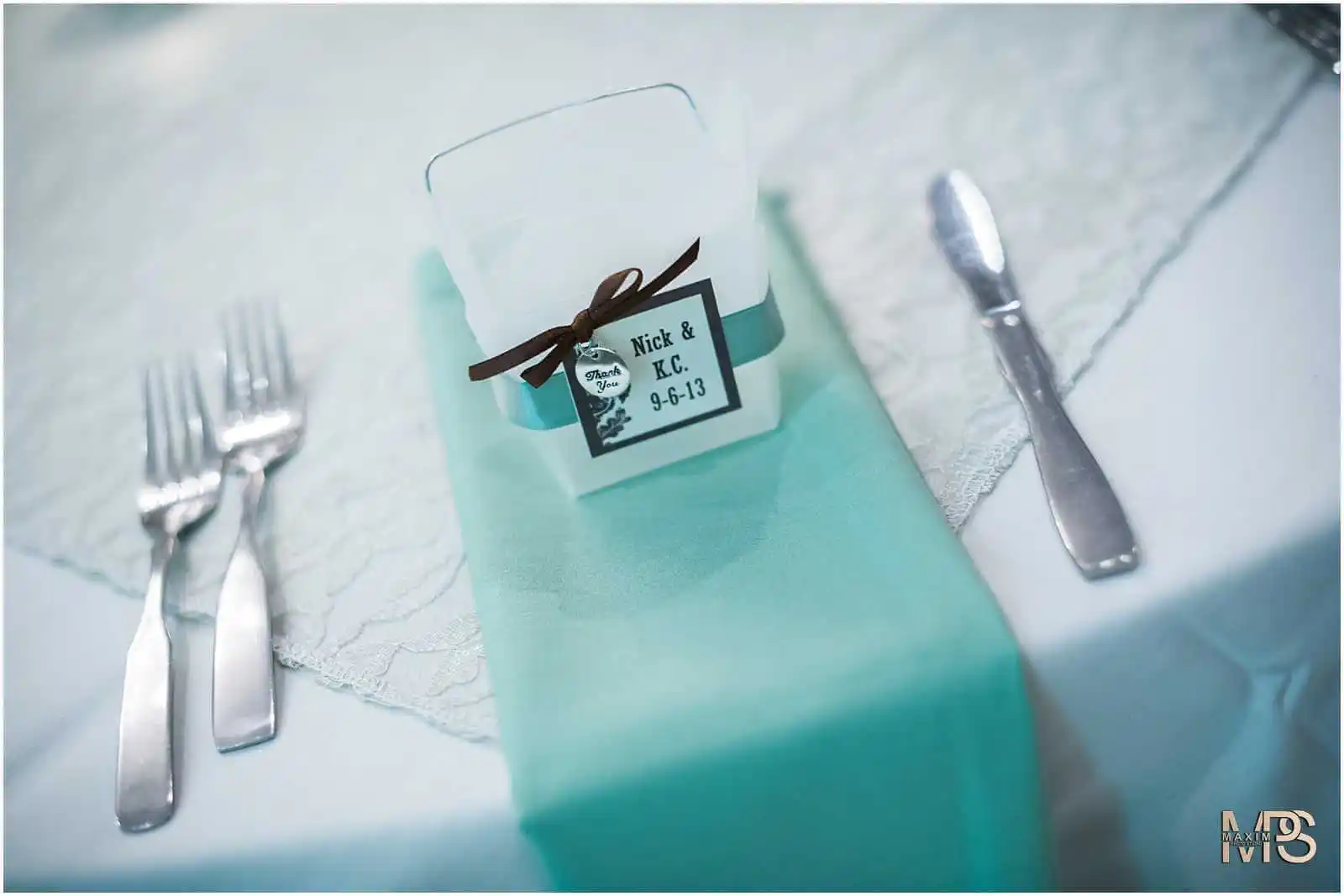 Elegant wedding table setting with personalized favor and teal accents.