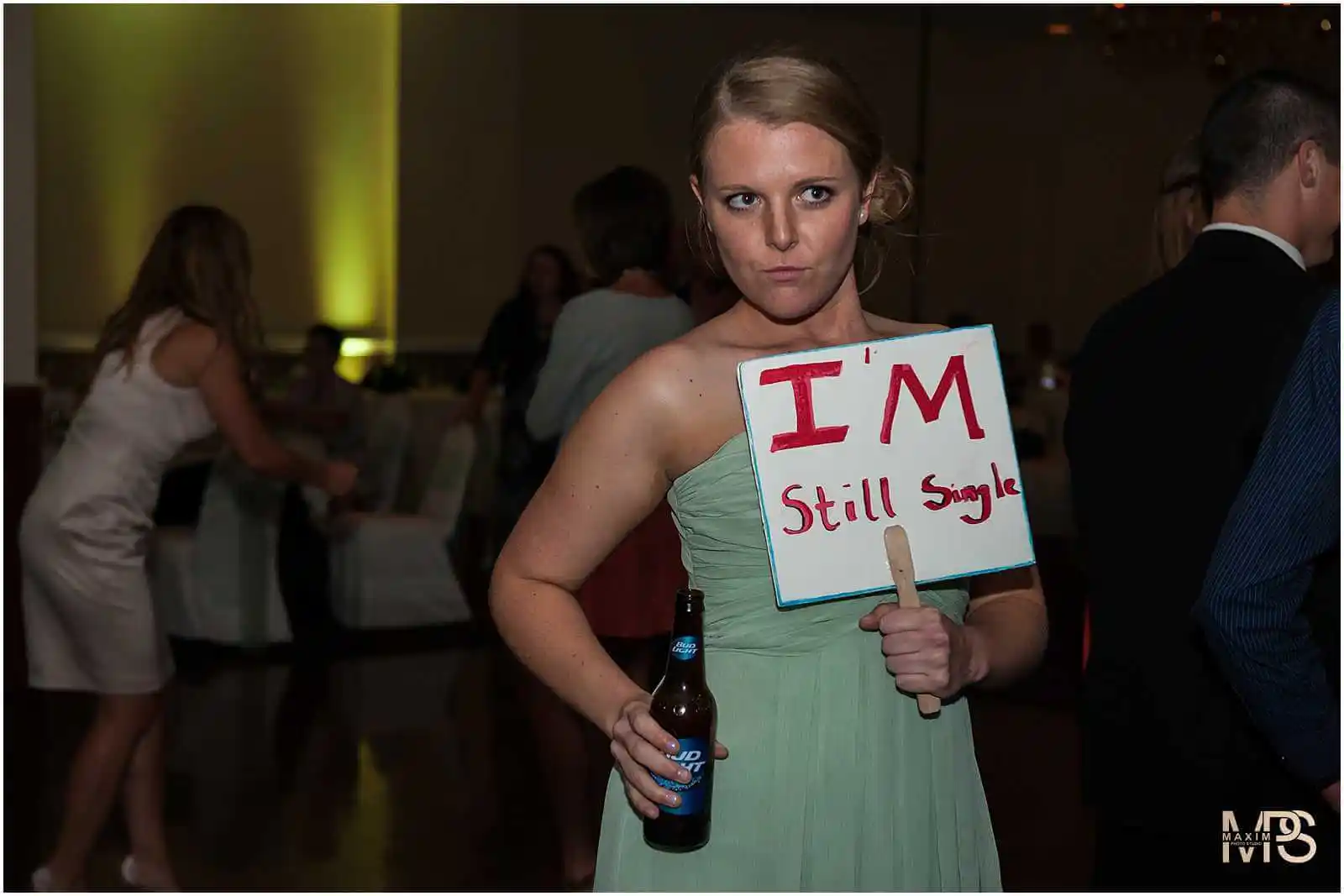 Woman at party holding a Im Still Single sign.