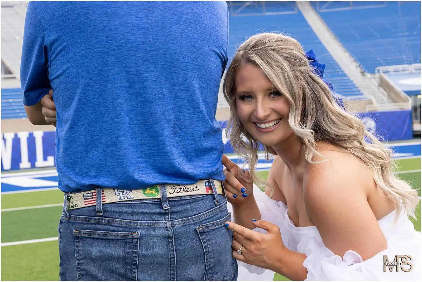 Bride laughing at grooms belt at UK Kroger Field engagement session