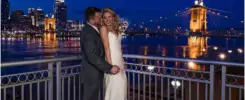 Romantic couple hugging by illuminated Roebling bridge at night Marriott Rivercenter Covington KY wedding.
