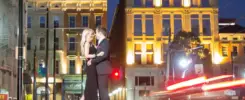 Couple engagement photo with nighttime city lights in Cincinnatis OTR district.